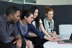 Grupo de jovens sentados em frente ao notebook discutindo alguma atividade.